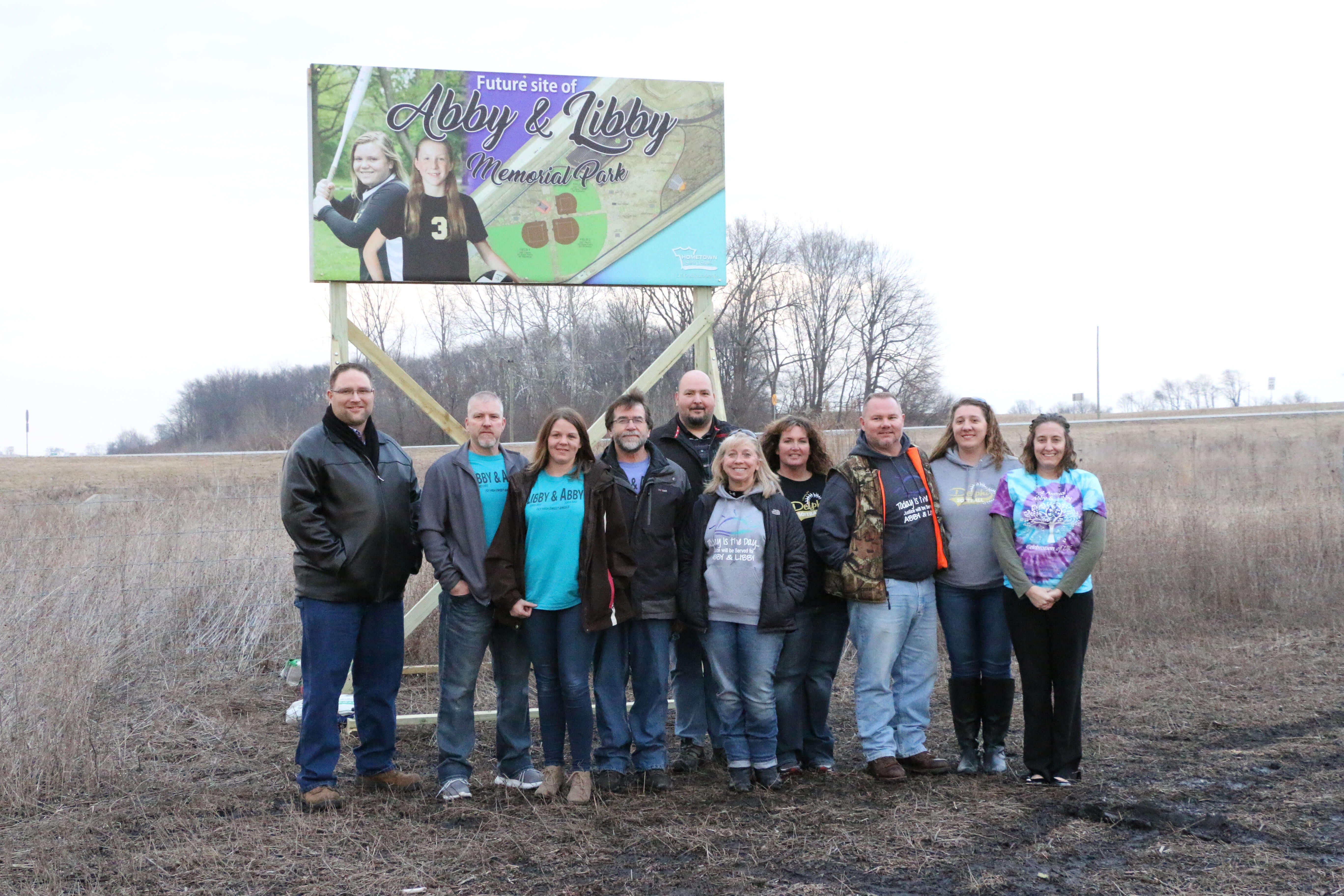 Family and Friends
			   standing in front of Abby and Libby Memorial Park Billboard